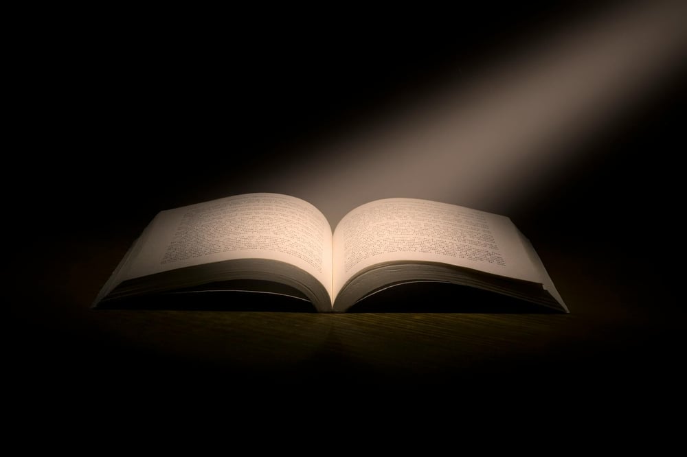 A beam of light shines onto the pages of an open book.