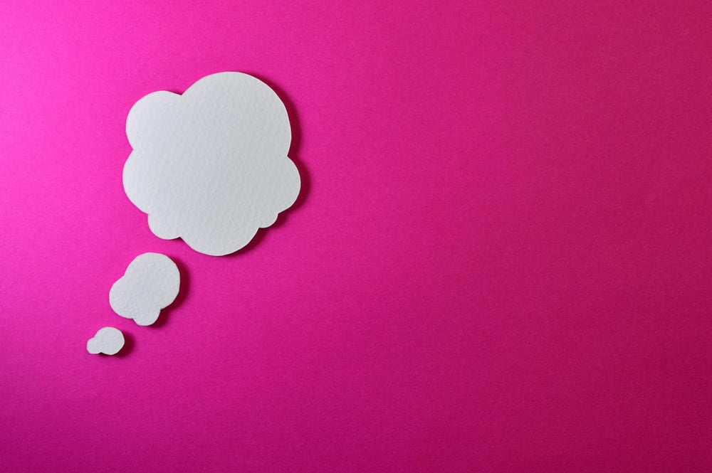 A white paper thought bubble on a hot pink background.