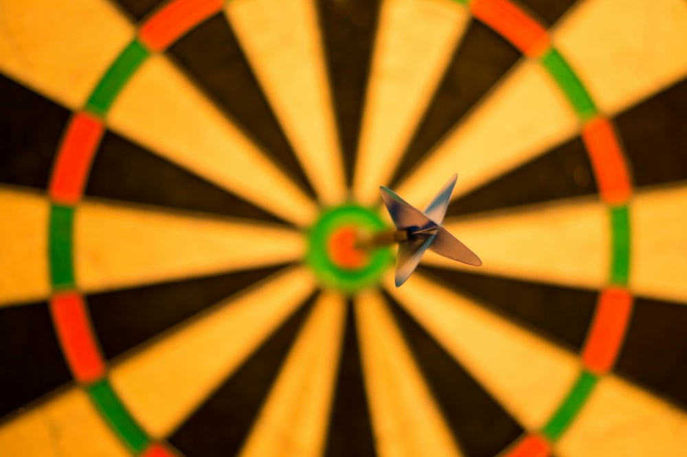 A dart in the bullseye of a dart board.
