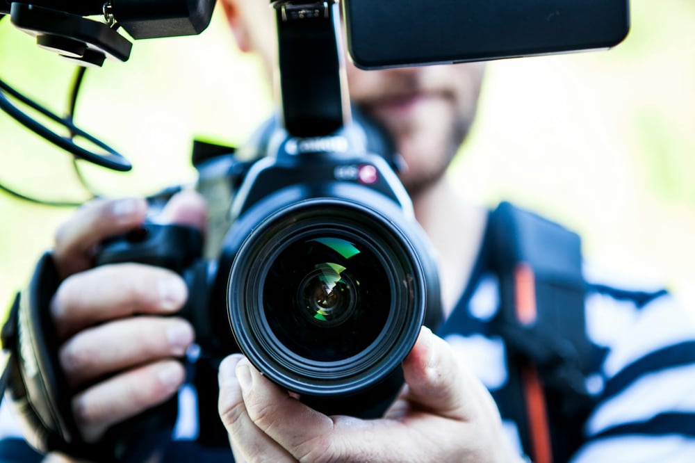 A large movie camera held a blurred out camera operator.