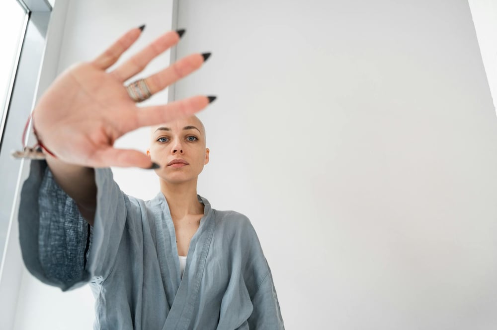A person in a blue robe with dark, pointed fingernails holds out their hand in a