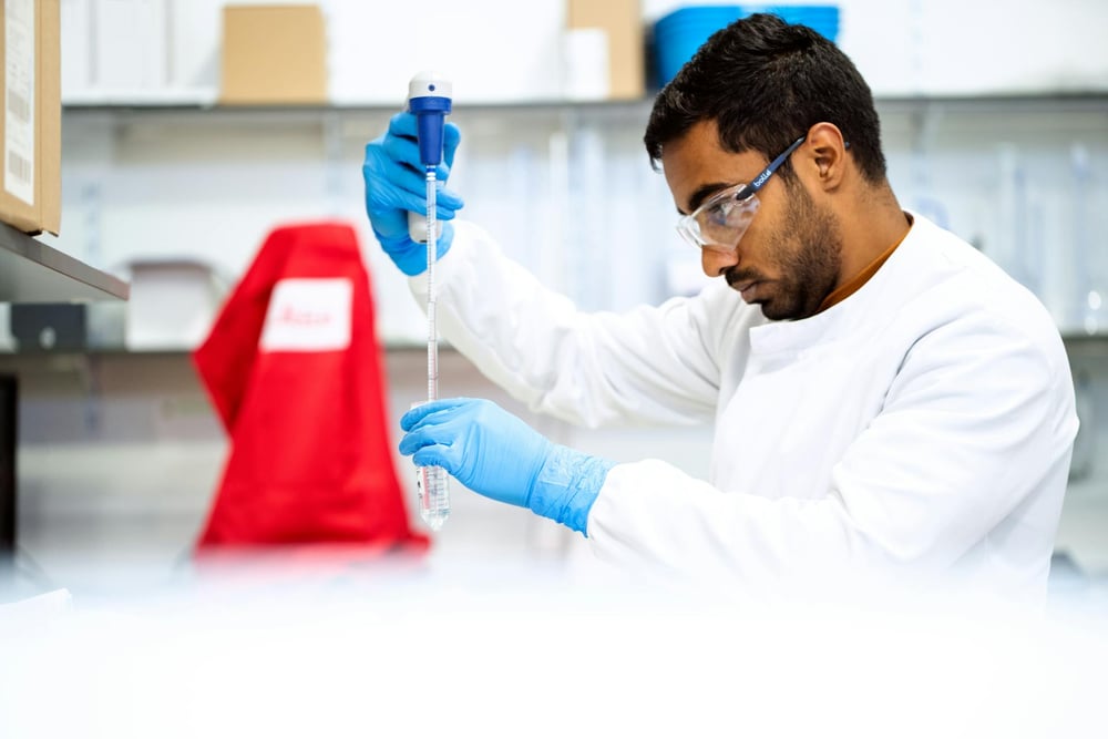 A scientist looks at something in a test tube.