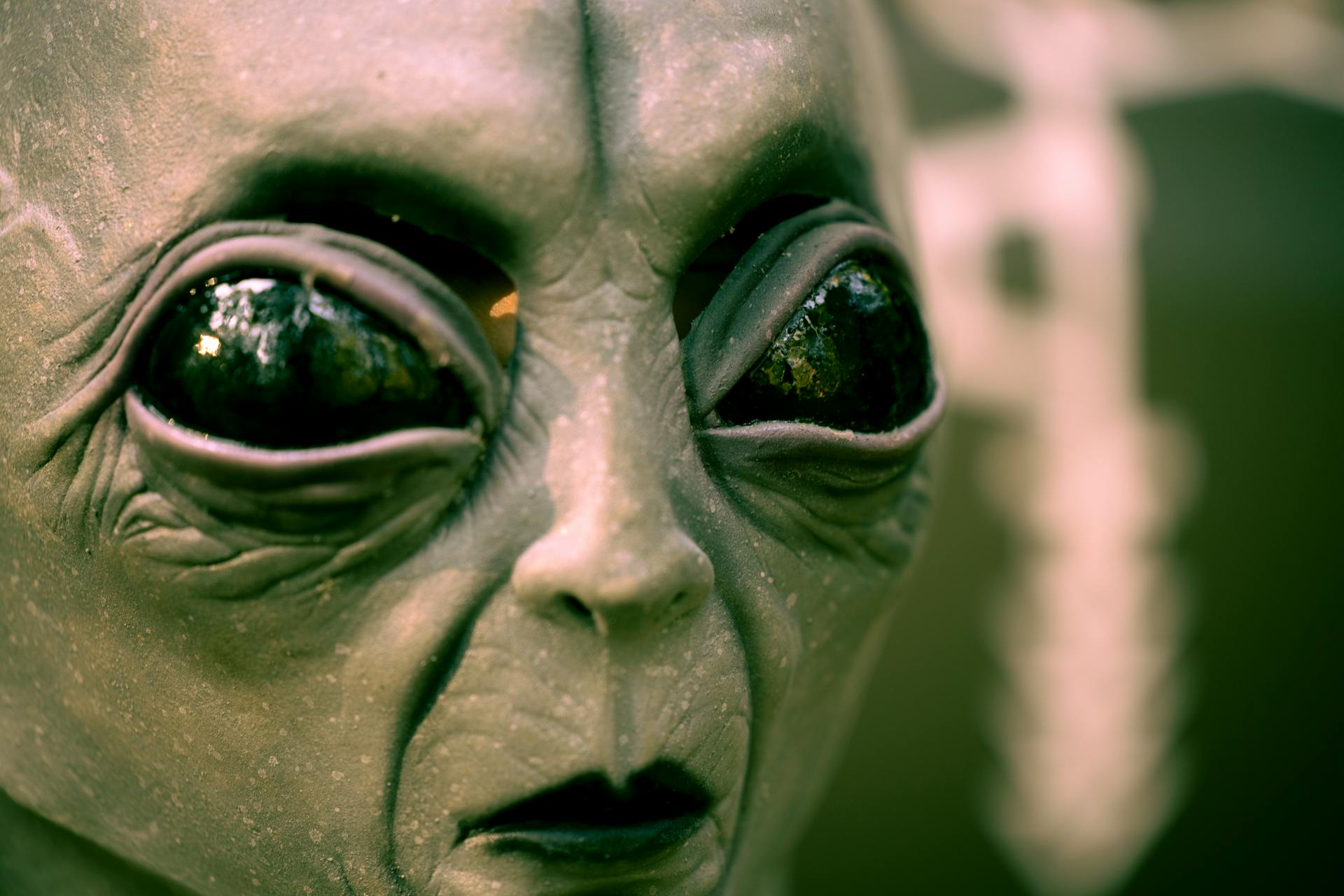 Close up of an alien's face with large black eyes.