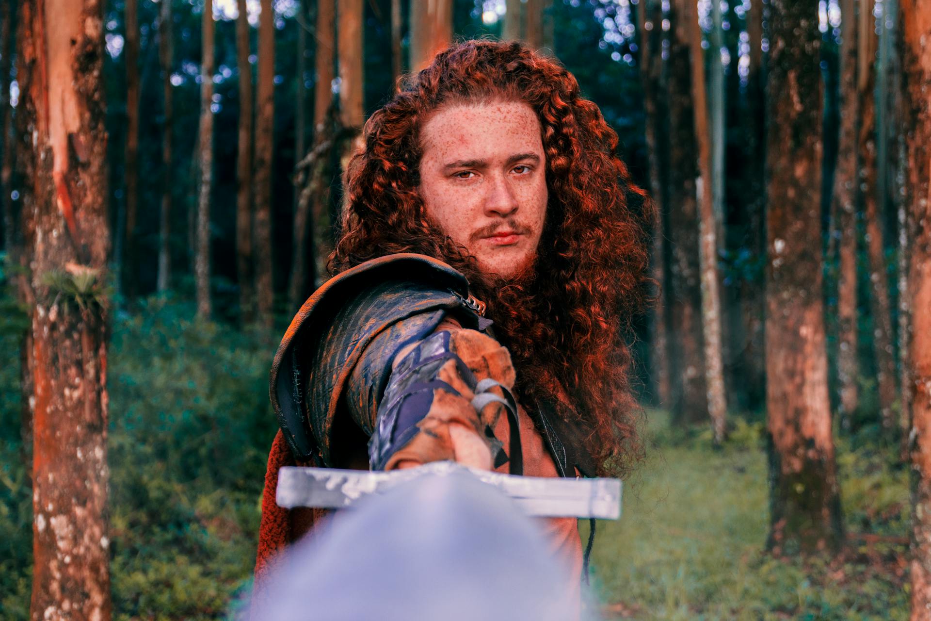A hero with long curly hair holds out a sword.