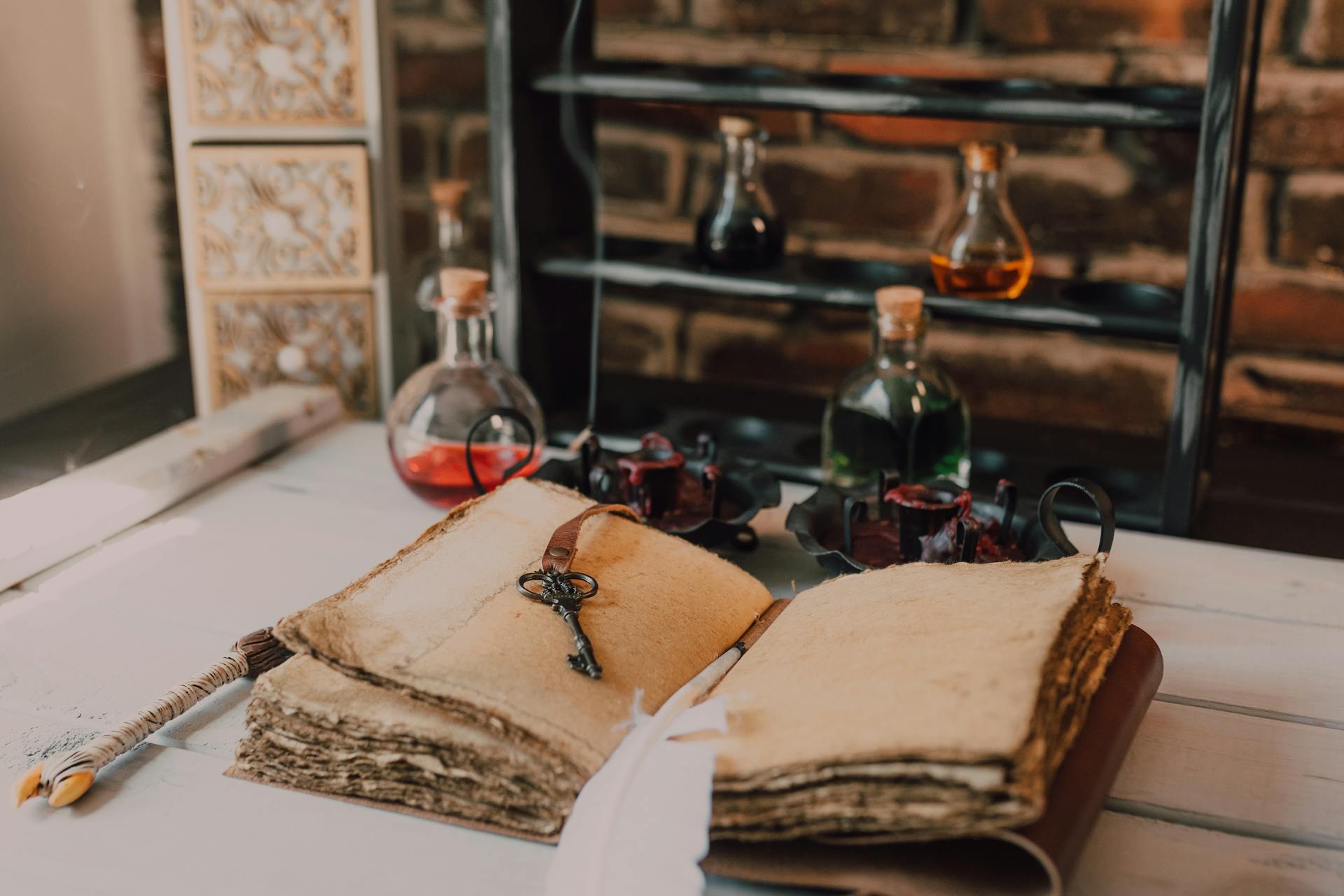 A key and feather quill sit on an open, leather-bound journal beside magic potions.