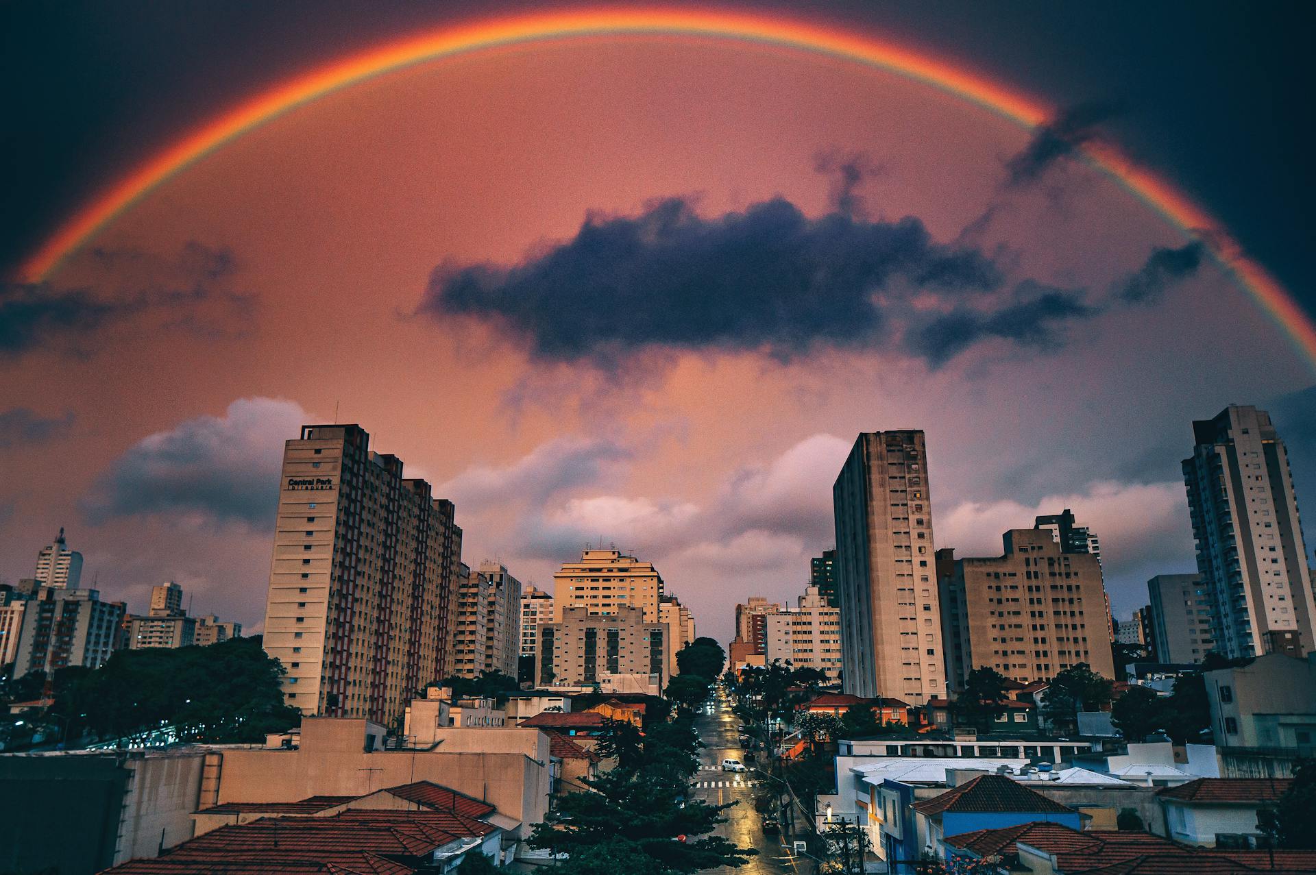 A city with a huge rainbow around it, creating a snow globe effect.