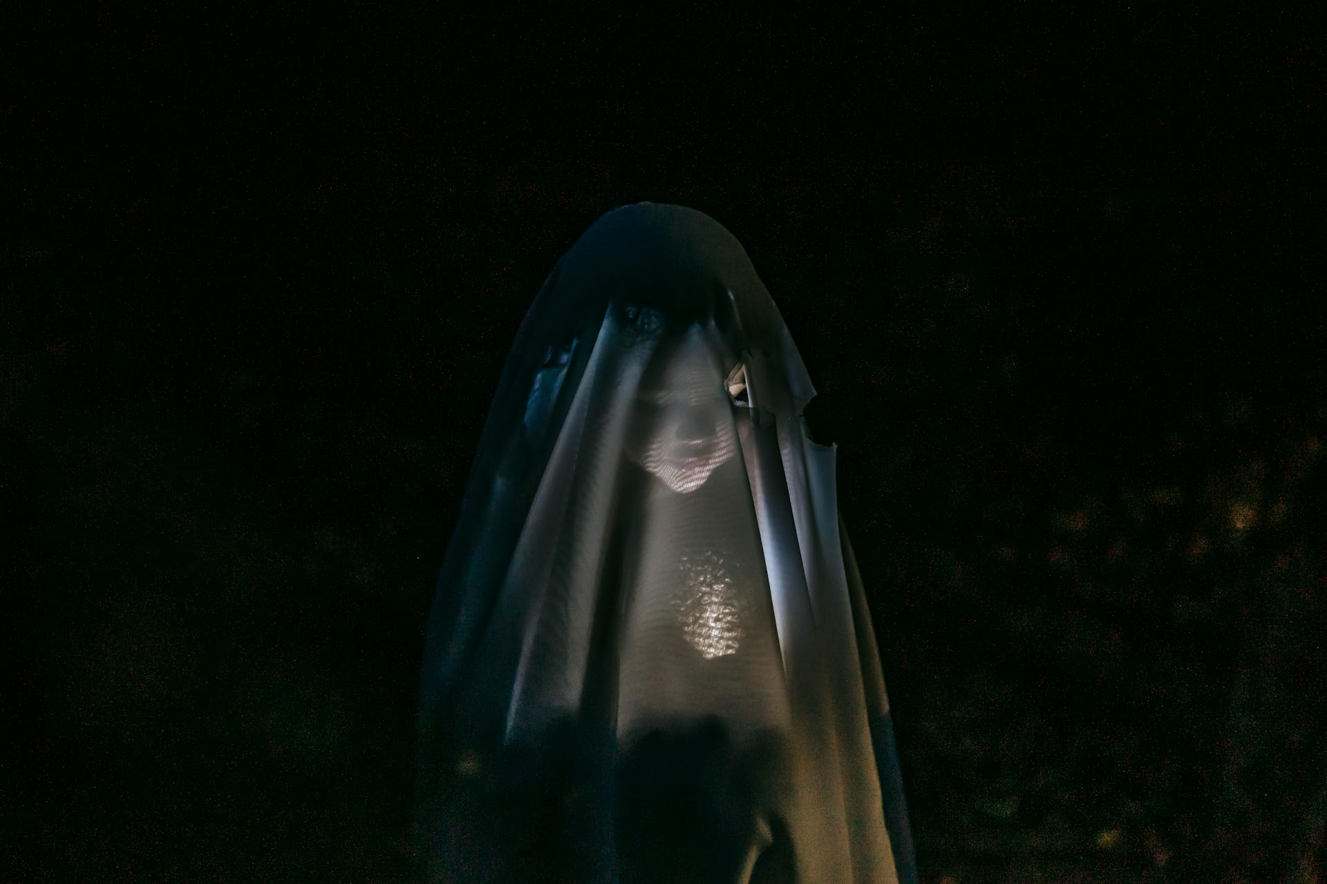A child covered in a black veil.