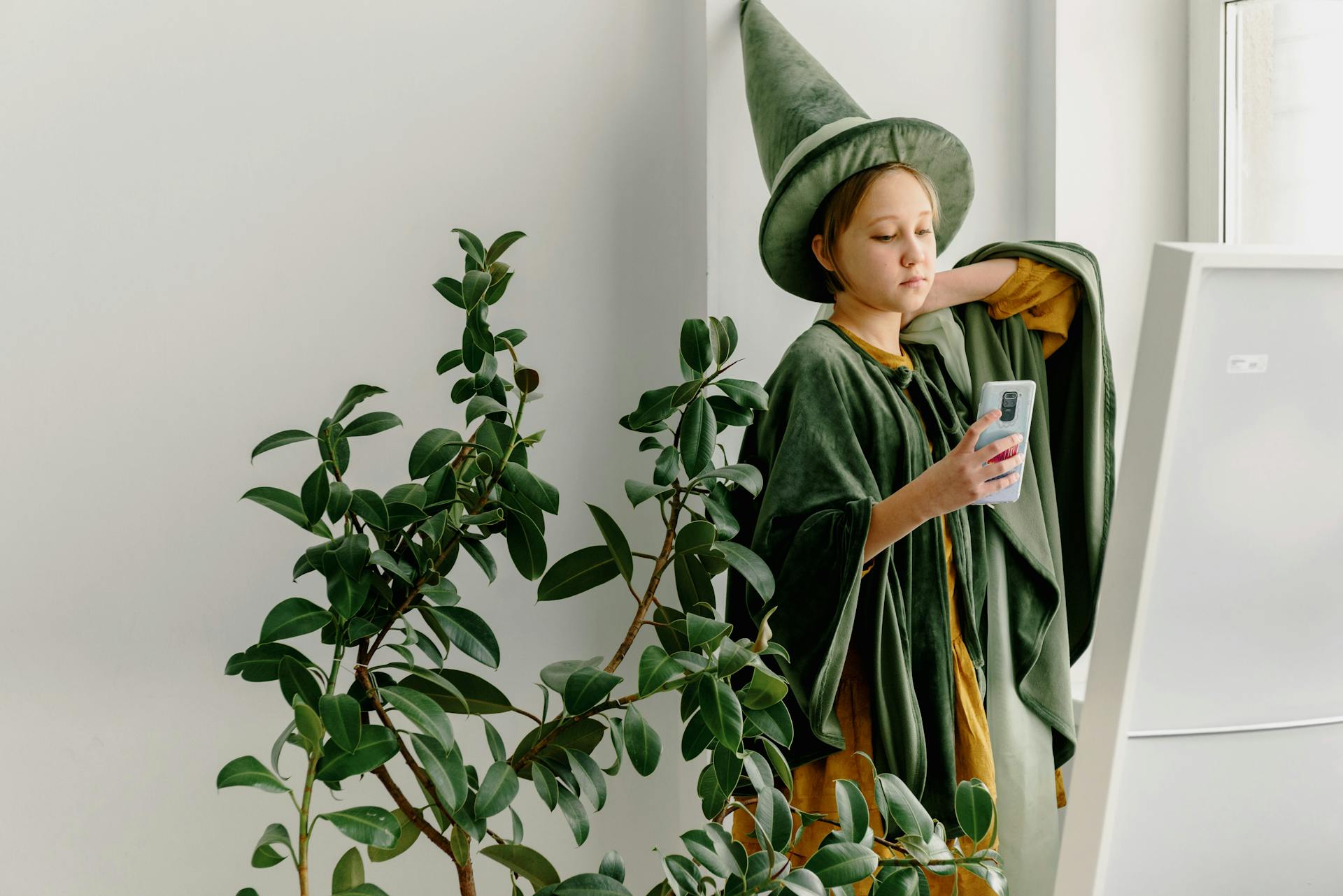 A child dressed as a wizard reads a phone screen.