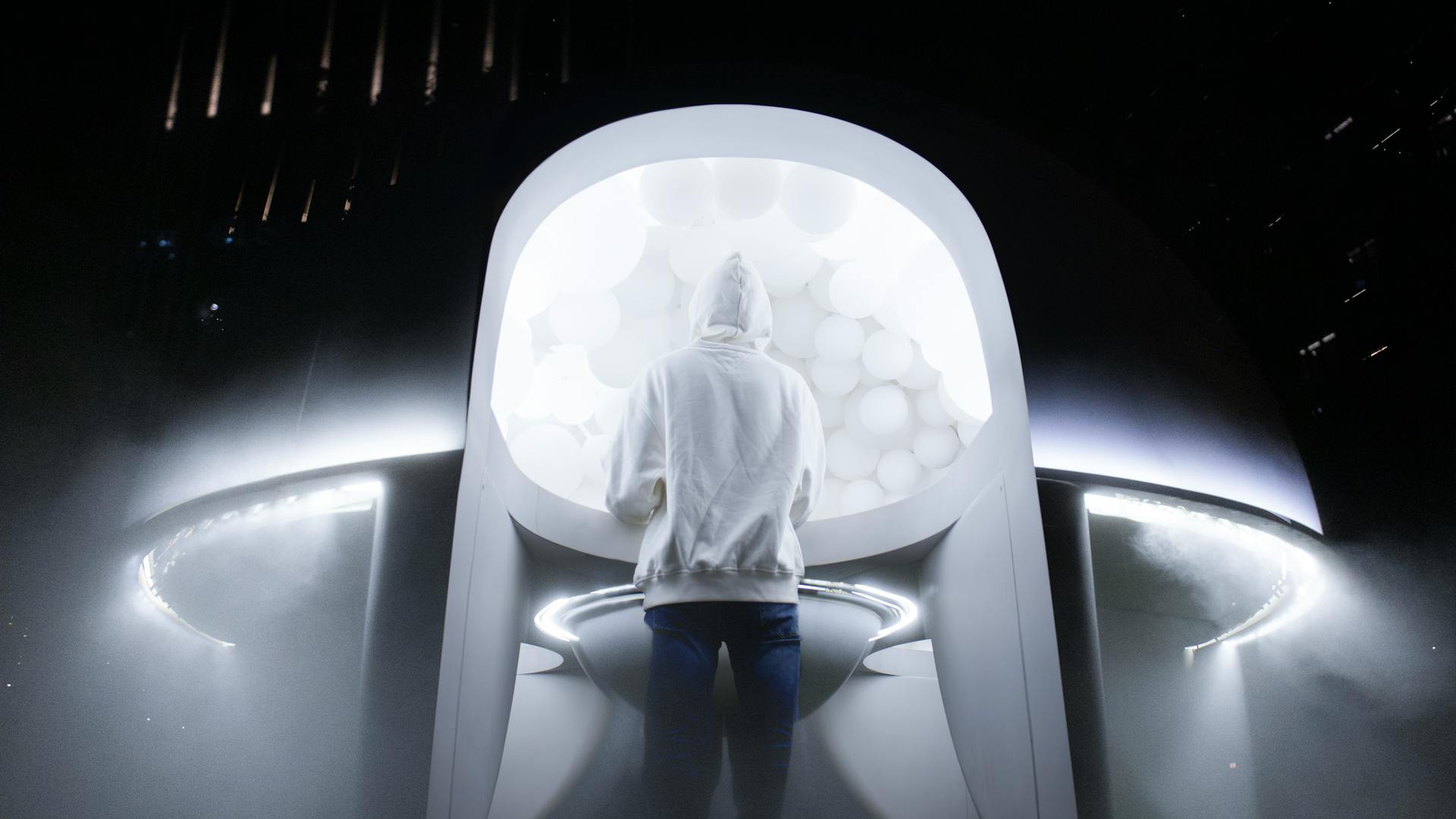 A person in a white hoodie standing in front of an alien spaceship.