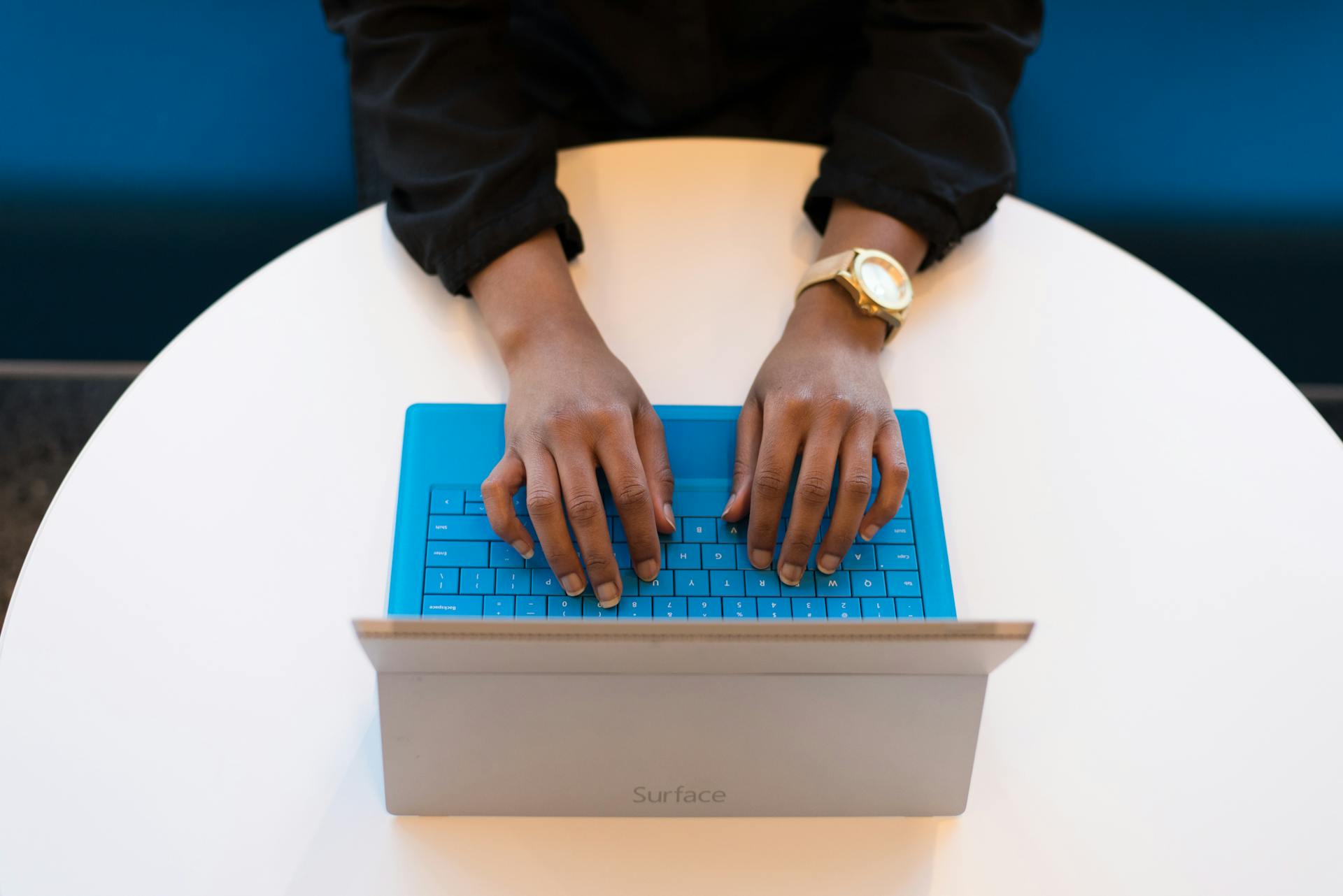 Hands typing on a blue computer keyboard.