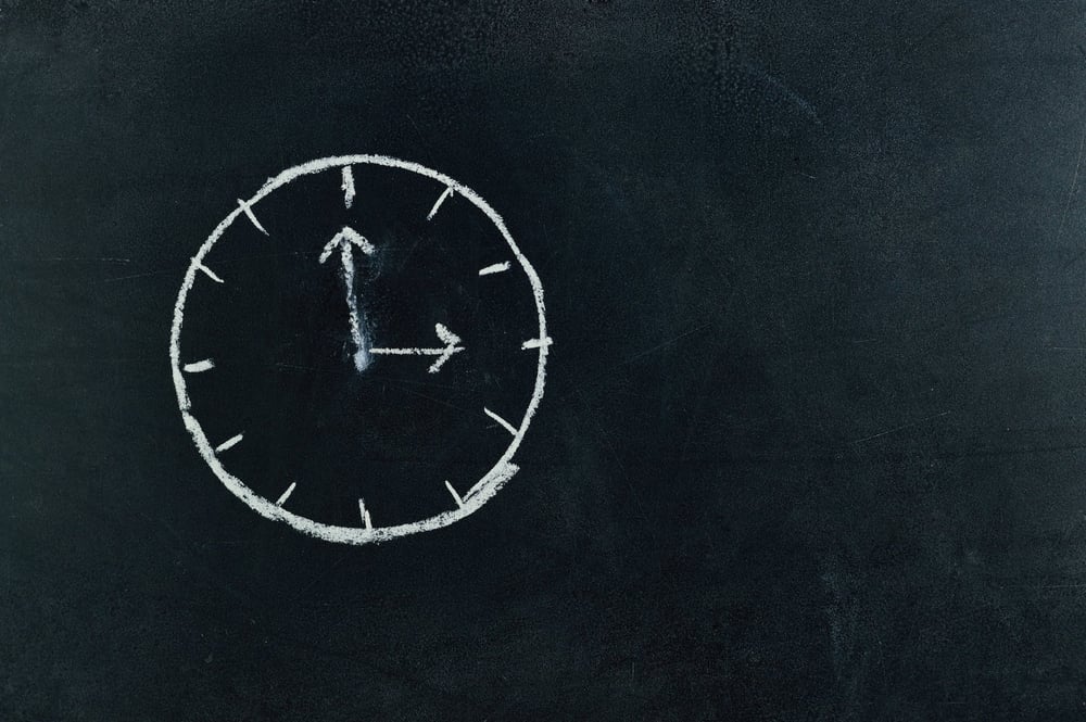 A clock drawn in chalk on a blackboard.