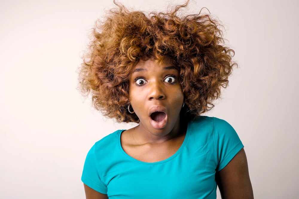 A person in a teal shirt making a surprised face.