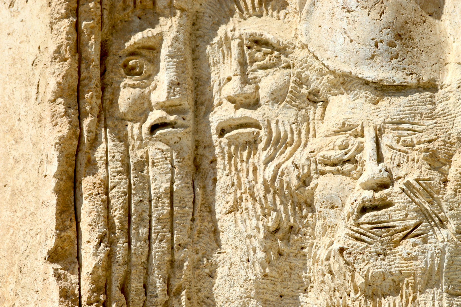 The faces of worried-looking characters carved into stone.