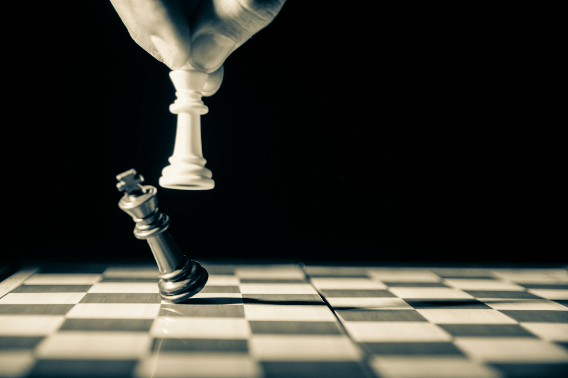 A white chess piece knocks over a black chess piece.