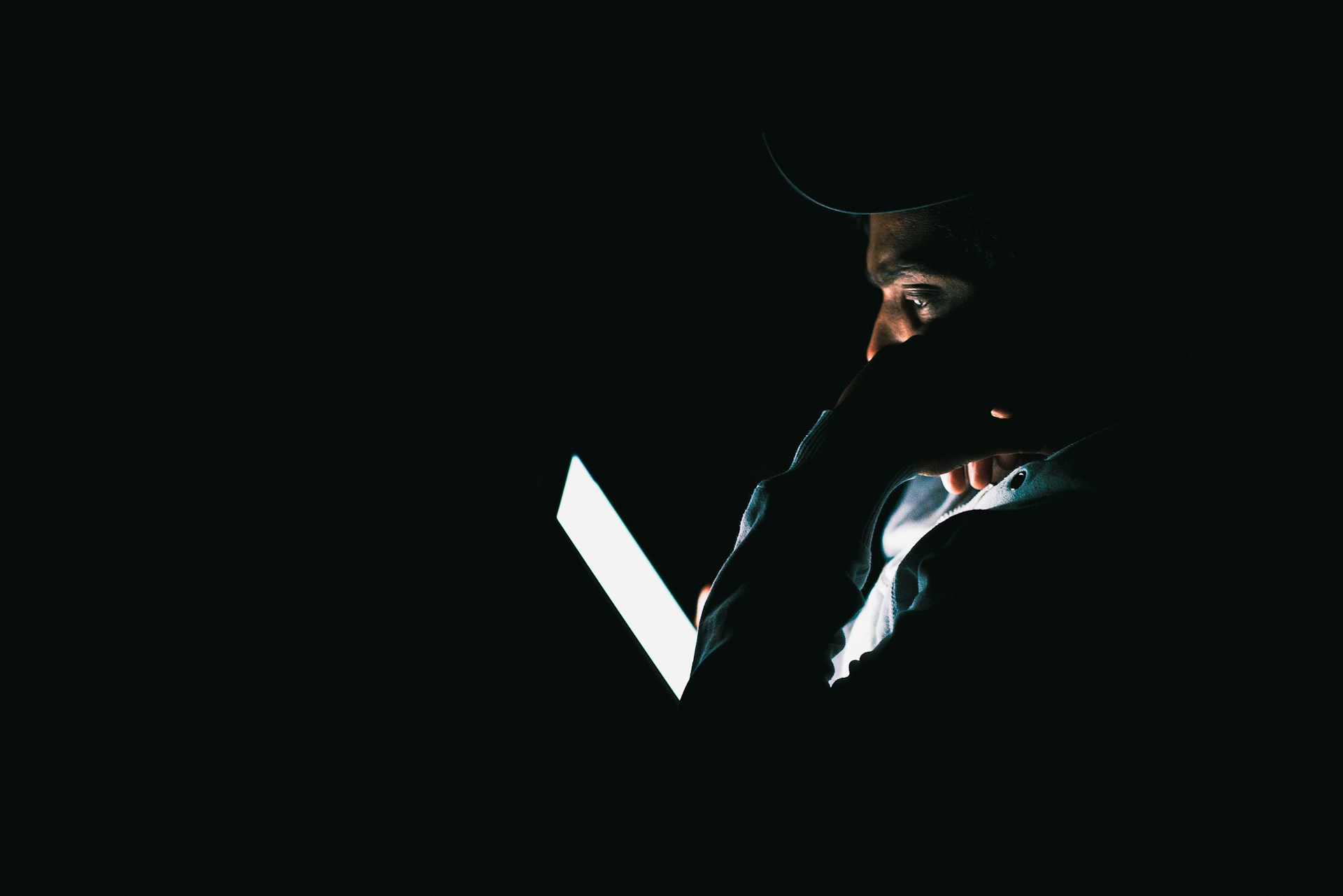 A person sits in the dark reading on an e-reader.