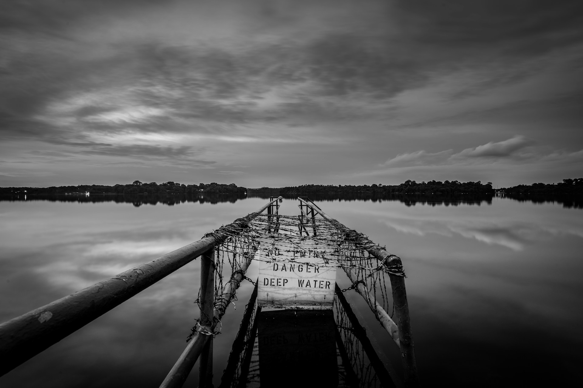 A sign on a dark lake reads,