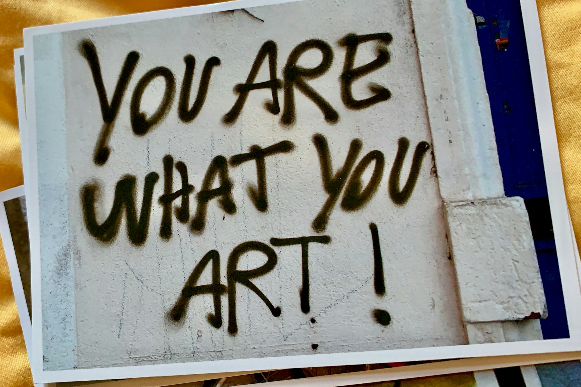 A stack of photographs with the one on top depicting a spray painted wall that says