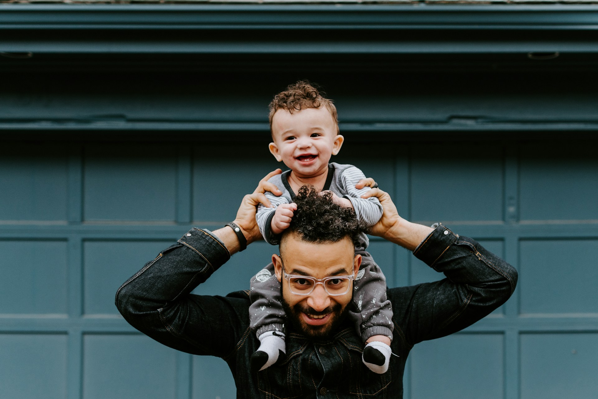 A person holds a baby on their shoulders.