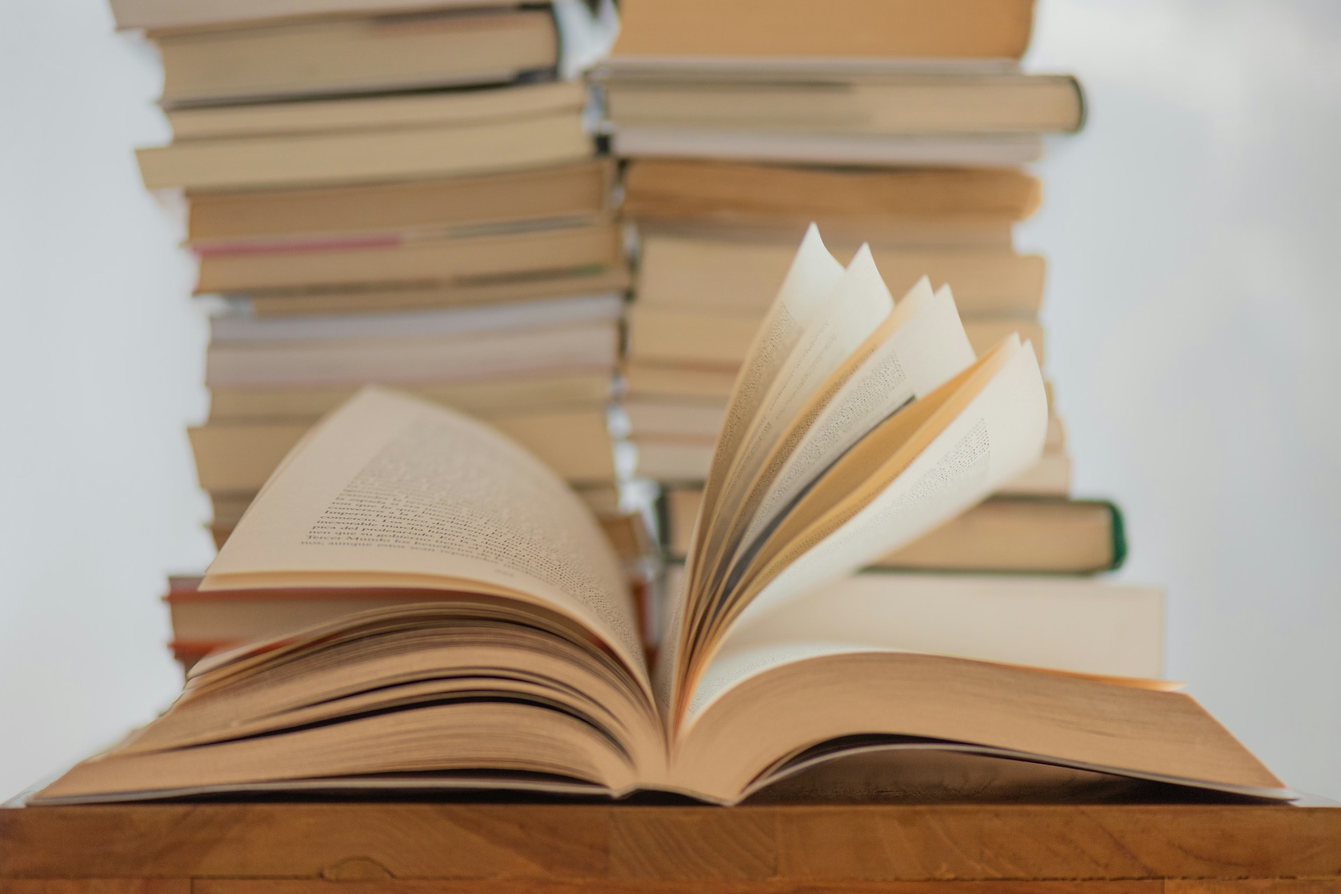 A book fans open in front of two stacks of books.