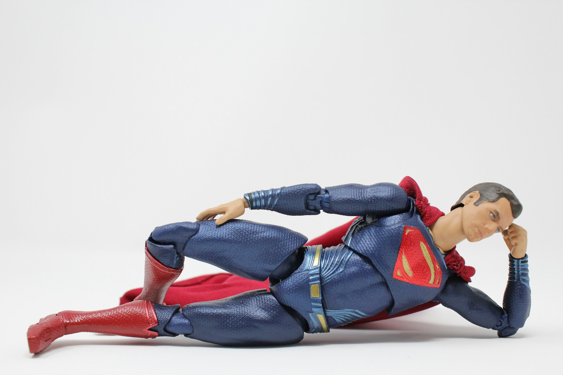A Superman action figure is posed in a reclining position.