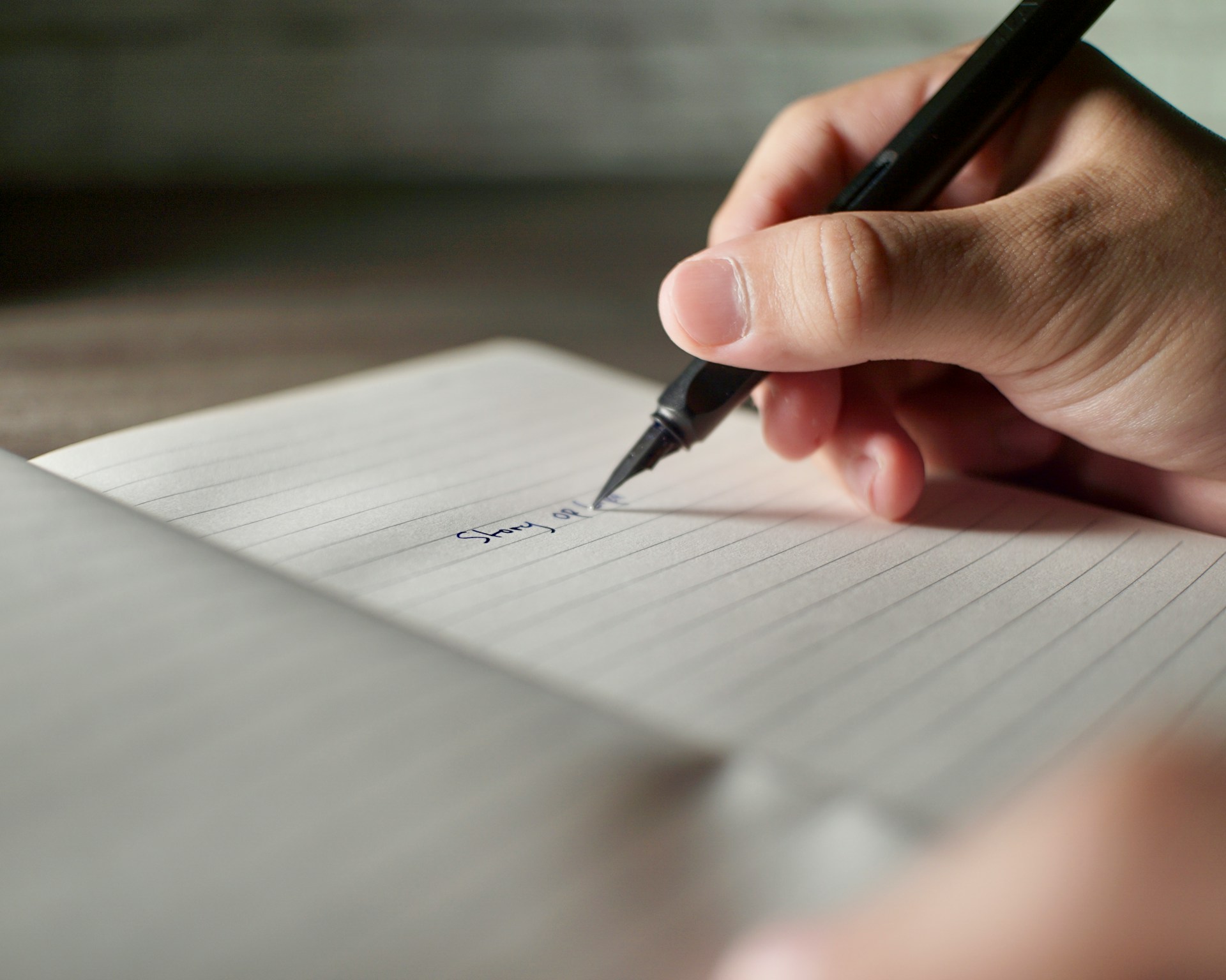 A hand writes in a notebook with a fountain pen.