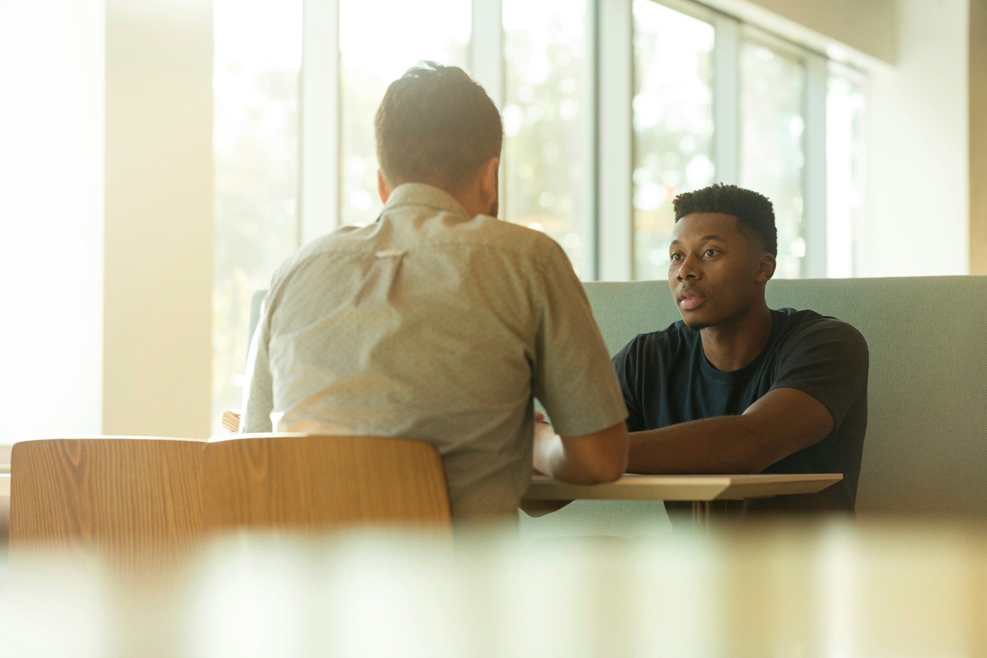 Two people have a conversation at a table.