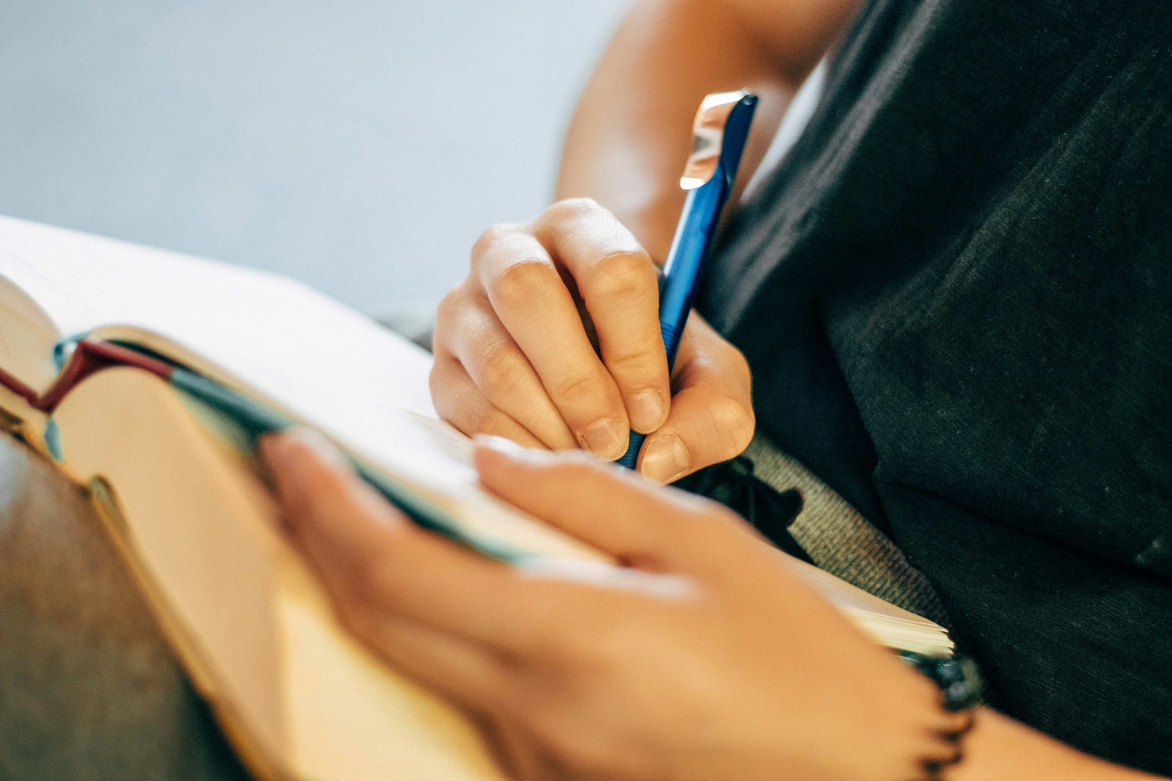 A hand writes in a notebook.