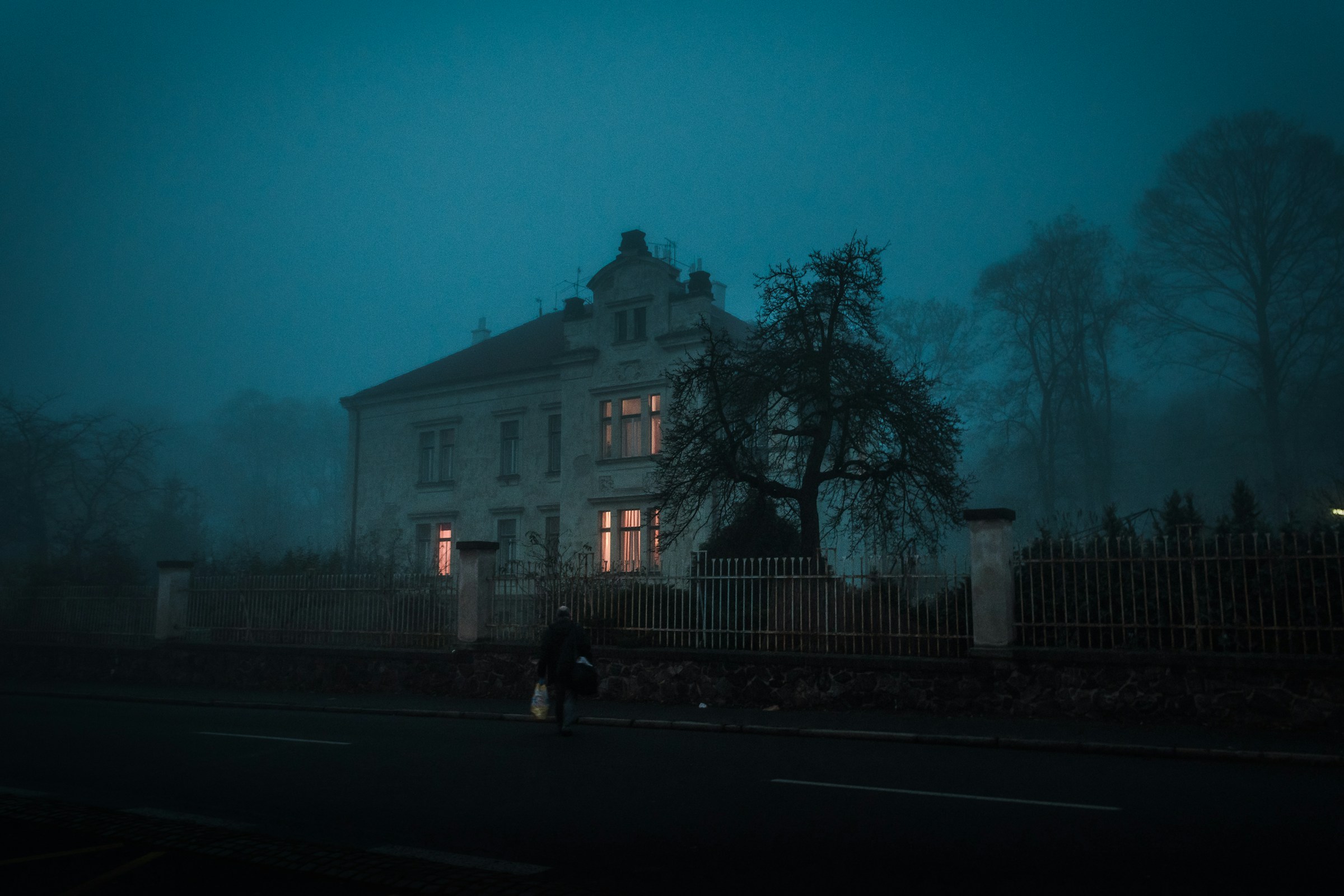 A creepy looking house in a on a shadowy blue evening.