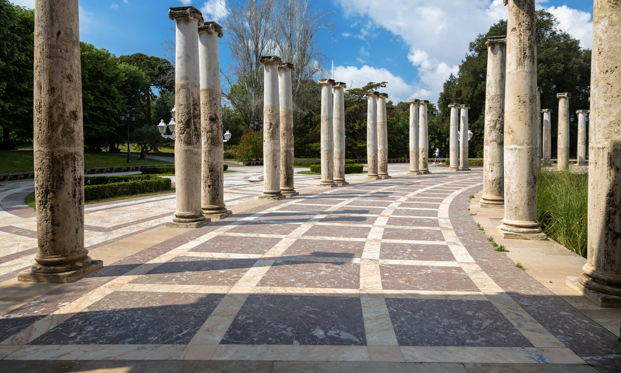 Ruins of an ancient road lined by pairs of parallel columns.