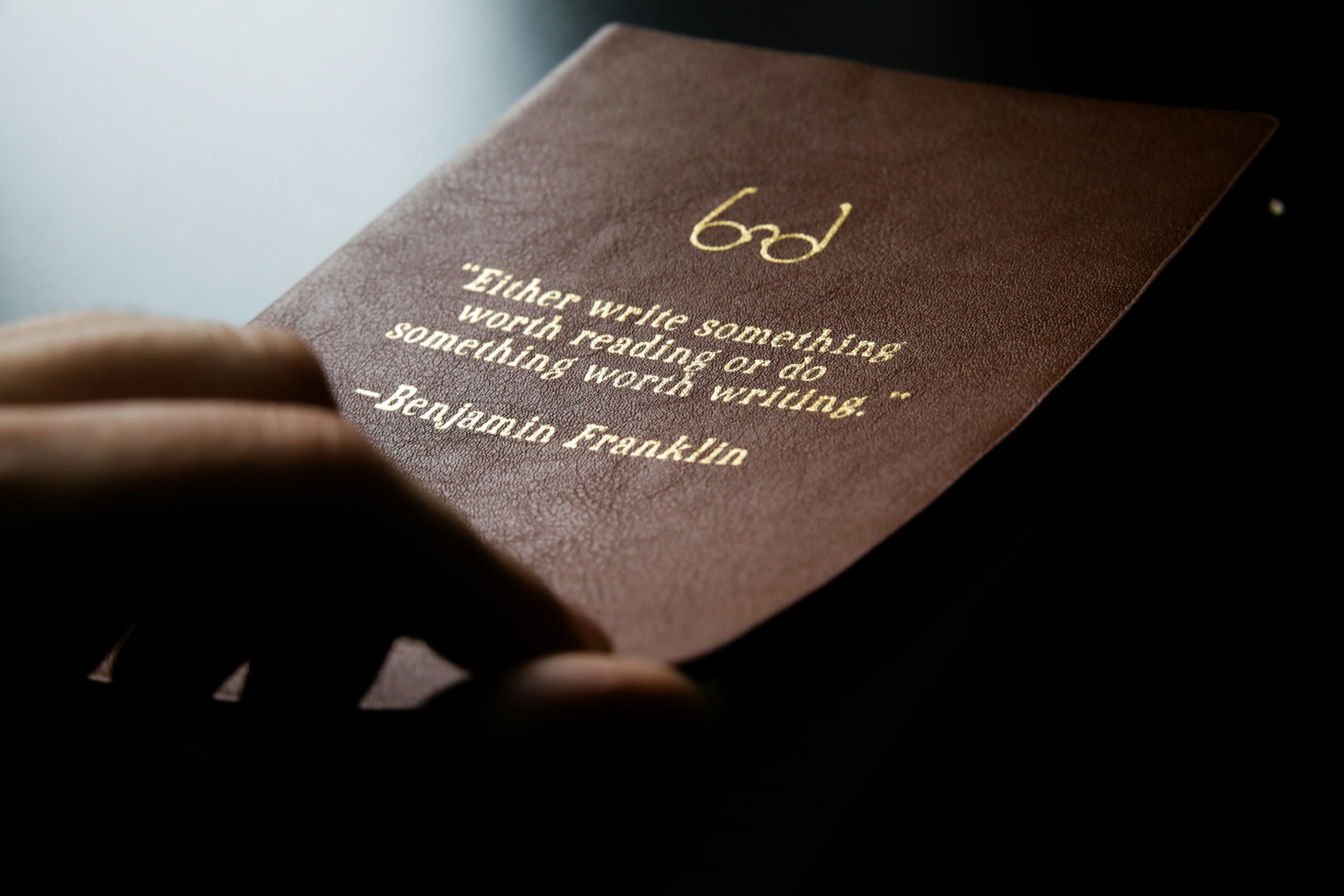 A brown leather journal with gold words reading,