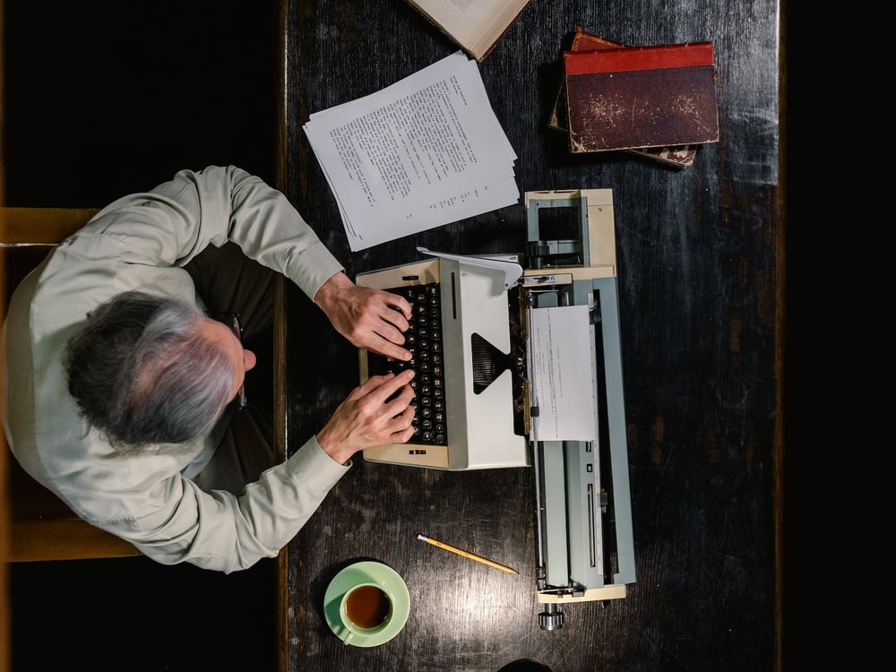 Overhead view of a person typing on a vintage typewriter.