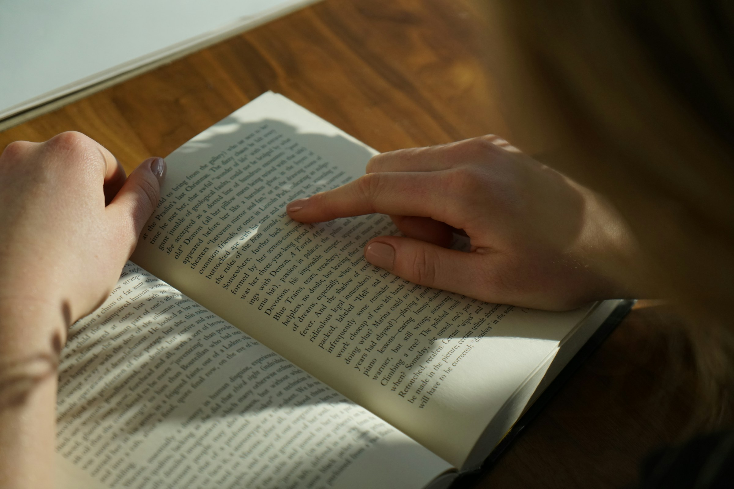 A finger traces a line of text in a book.