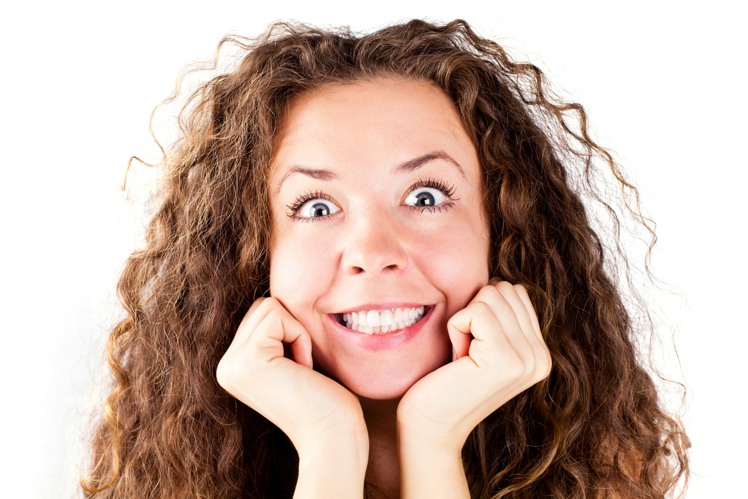 A person with curly hair smiling big with wide eyes.