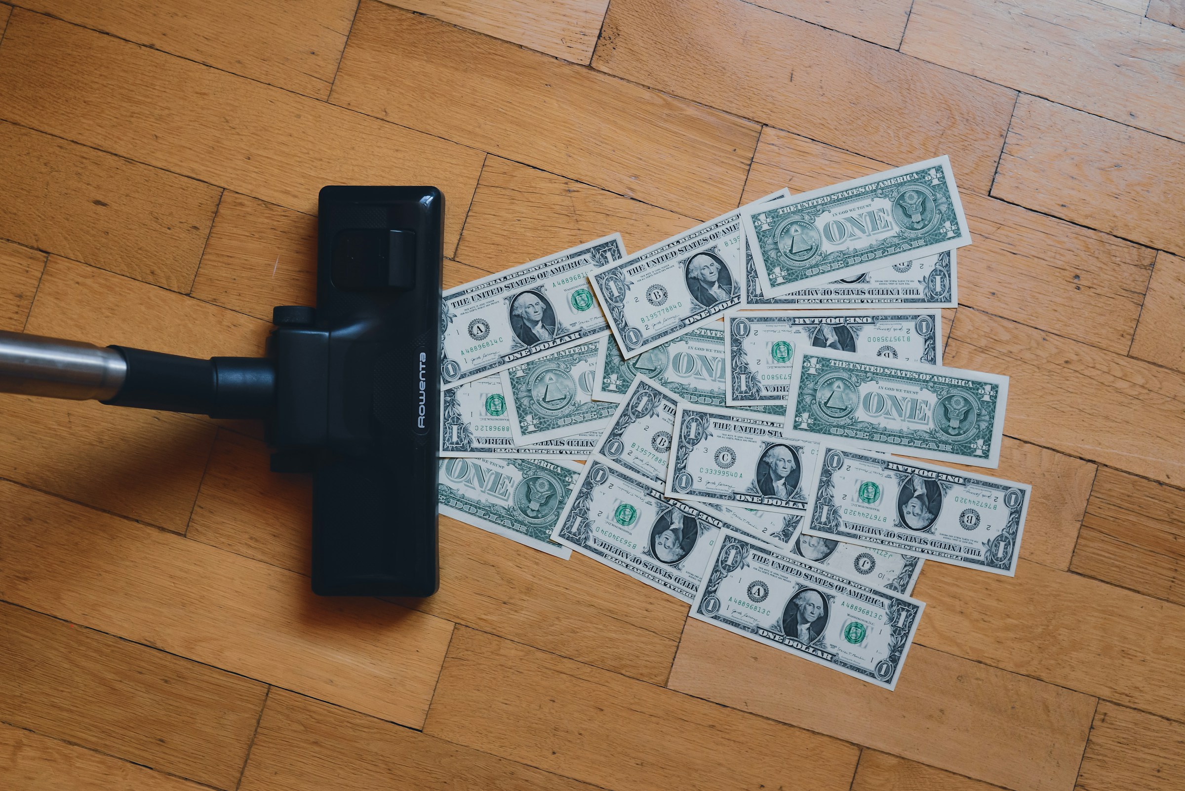 A vacuum cleaner sucks up dollar bills.