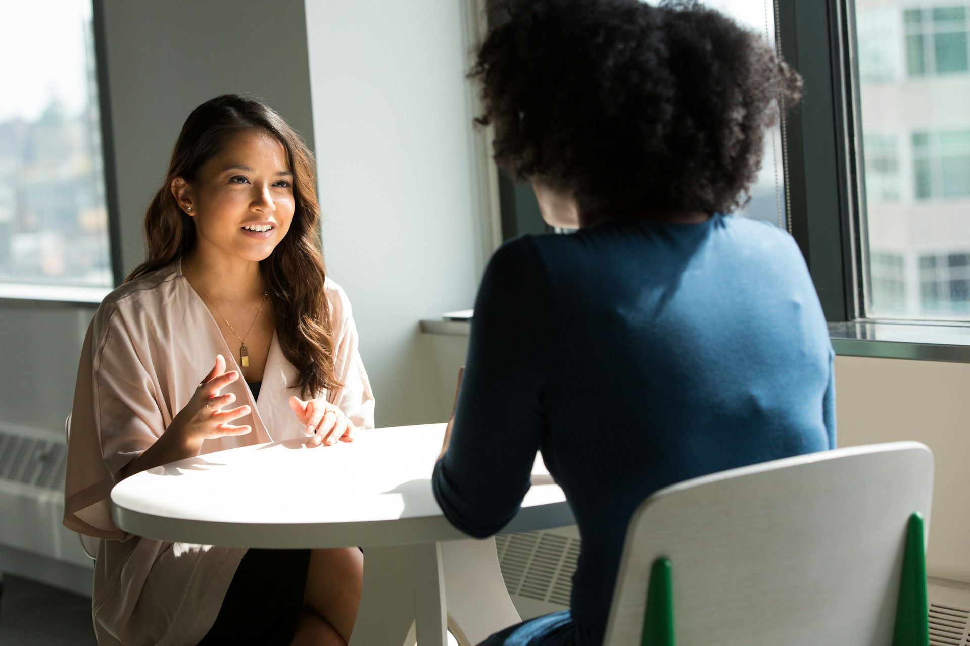 Two people have a conversation at a small table.